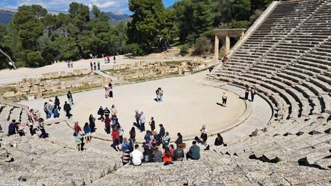 Tourists exploring an ancient amphitheater with stone steps.