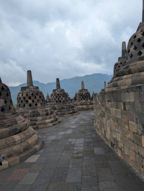       A historical temple with bell-shaped structures on a mountain path.
  
