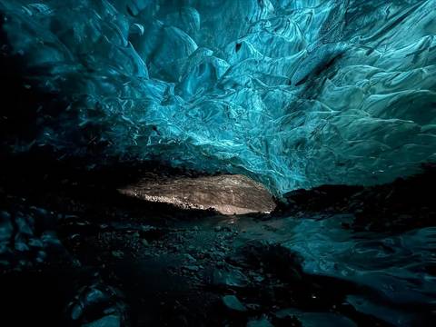 Inside of a strikingly blue ice cave with textured ice formations.