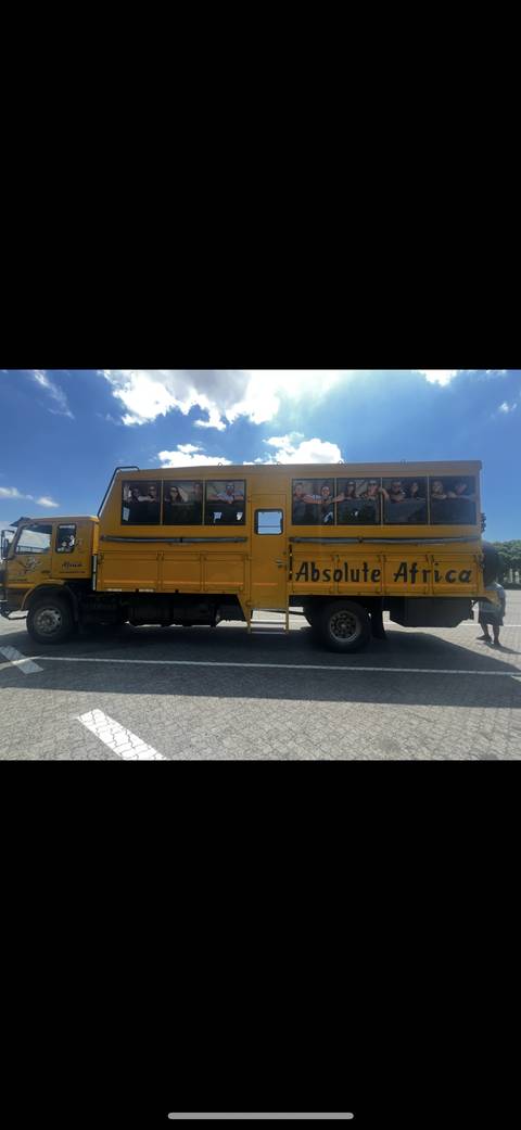 Bustling city street with people looking out from the windows of a yellow bus.
