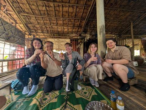       Group of people sitting indoors smiling at the camera.
  