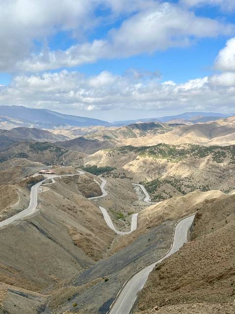 A winding mountain road through barren, hilly terrain.