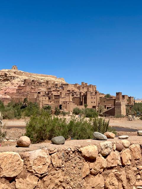 A view of Ait Benhaddou with stone buildings in a desert landscape.