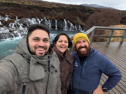       Three people smiling with a backdrop of a waterfall.
  