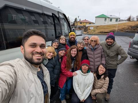       Group of people posing in front of a bus in a residential area.
  