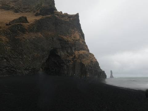       Rocky coastline with dramatic cliffs and overcast sky.
  