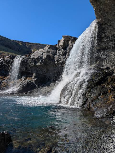       Waterfalls cascading over rocky cliffs into clear waters.
  
