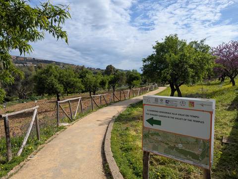       Pathway in a green garden with a directional sign.
  