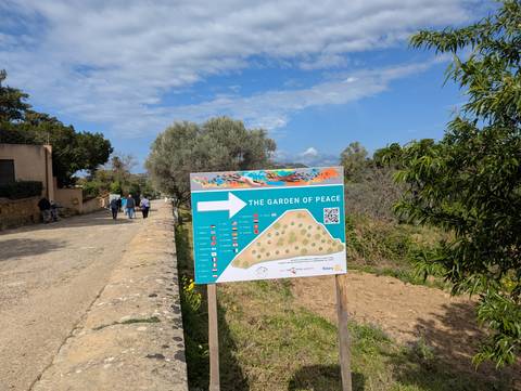       Signpost in a park with people walking in the background.
  