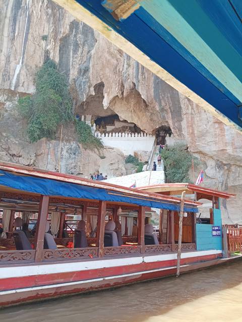 Entrance of a temple carved into a rock face with boats in the foreground.