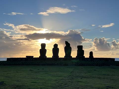 Silhouette of Moai statues at sunset on Easter Island.