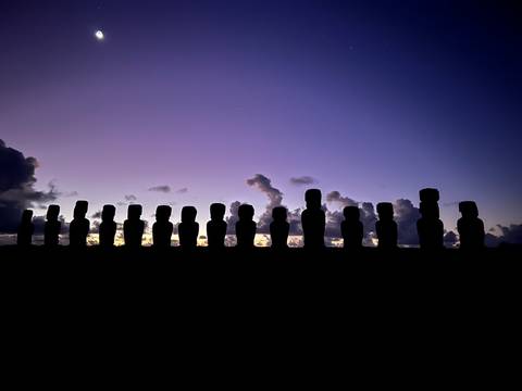 Silhouette of Moai statues at dawn on Easter Island.