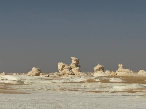       White rock formations in a desert landscape under clear skies.
  