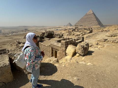       Tourist wearing a headscarf viewing the pyramids in Giza.
  