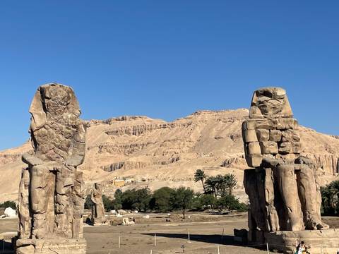 Colossi of Memnon statues with desert mountains in the background.