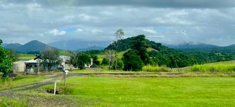 Pastoral landscape with hills and cloudy skies.