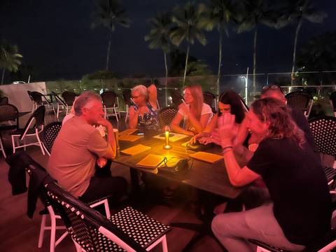       A group of people sitting around a table with a candle at night.
  