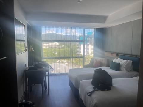       An interior view of a hotel room with large windows showing cityscape and mountains.
  