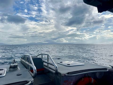       Ocean view from a boat under a cloudy sky.
  