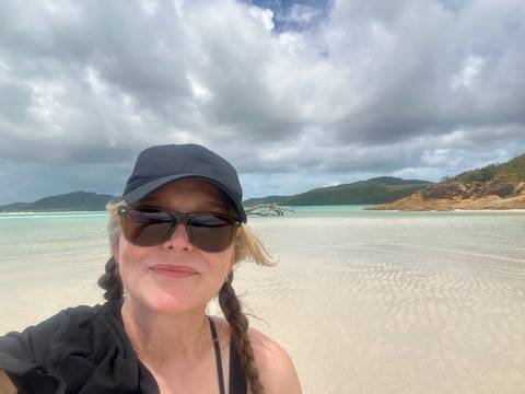       Person taking a selfie on a beach with cloudy skies.
  