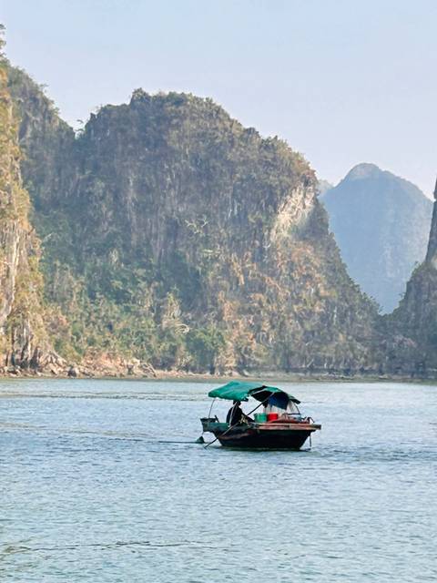 Boat on a river with limestone cliffs in the background.