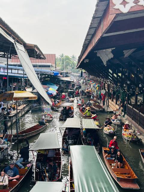 Floating market with boats selling goods on a canal.