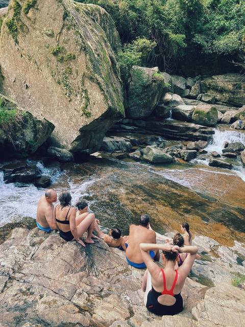 People sitting on rocks near a waterfall.