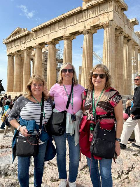       Group of women smiling in front of ancient columns.
  