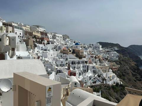       View of white buildings on a cliff with a blue dome.
  