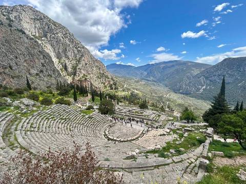       Ancient amphitheater with mountains in the background.
  