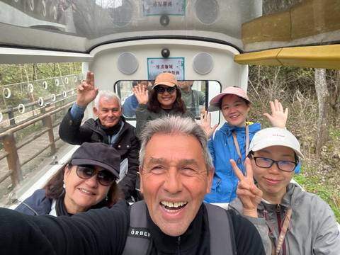       Tourists smiling and waving inside a sightseeing vehicle.
  