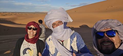       People posing in traditional attire in a desert setting.
  