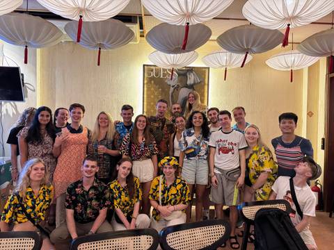       A group of people posing together indoors under decorations.
  