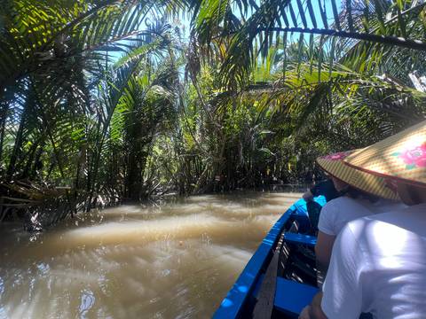 People in a boat navigating through a lush, tropical waterway.
