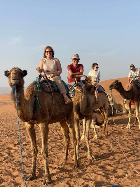 People enjoying a camel ride through the desert.