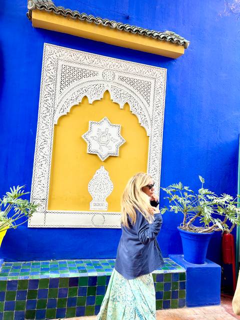 Person standing near a decorative wall with vibrant blue and yellow colors.