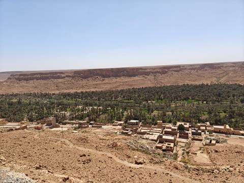 A rural desert landscape with scattered buildings and trees.