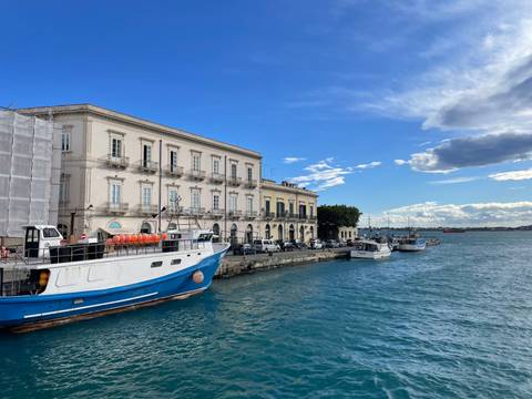 Coastal view with boats docked by an elegant building.