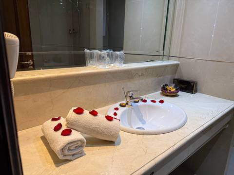 Bathroom sink with towels and decorative rose petals.
