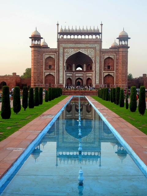 Imposing entrance to a historical Indian monument with carefully manicured gardens.