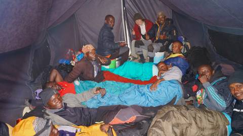 Several people in sleeping bags inside a large tent.