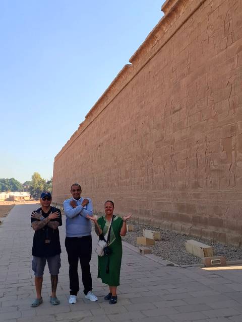 People posing in front of ancient wall with carvings