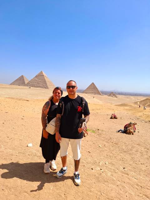 Two people standing in front of pyramids