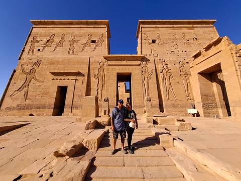 Two people in front of an ancient temple with carvings