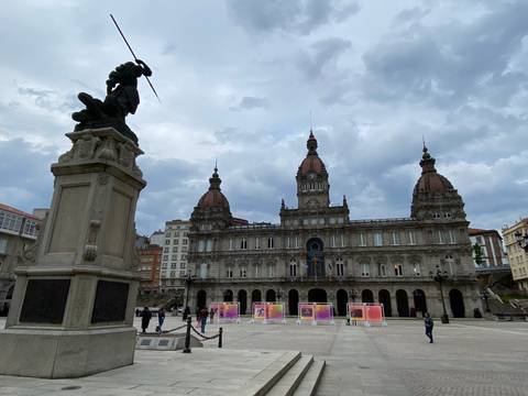 Large historic building with statues and a cloudy backdrop.