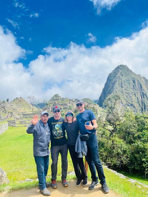       Group of people posing with Machu Picchu ruins in the background.
  
