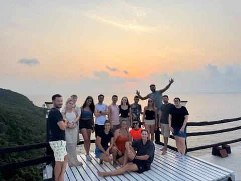 A group of people posing on a deck during sunset with the ocean in the background.