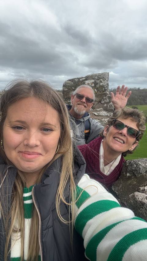 Group of three people with stone structure in the background.