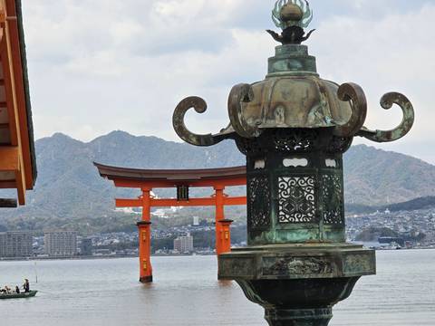 Traditional Japanese structure with water and mountains in the background.