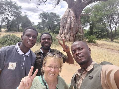       Group of people in front of a massive baobab tree.
  